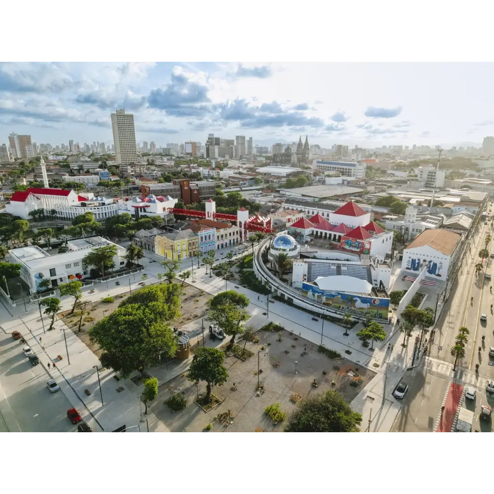 Vista aérea do Centro Dragão do Mar de Arte e Cultura em Fortaleza, destacando a praça arborizada, o planetário em formato de cúpula prateada e os prédios coloridos ao redor